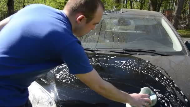 Panorama van jonge man schoon wassen zwarte favoriete auto met schuim — Stockvideo