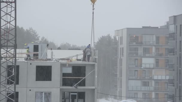 Queda de neve e trabalhadores do local de construção construir casa no inverno — Vídeo de Stock