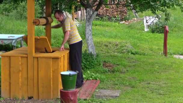 Arbeiter schöpfen vollen Eimer Wasser aus Holzlandbrunnen — Stockvideo