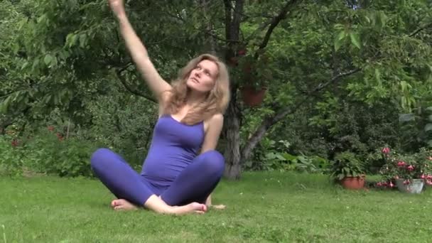 Healthy pregnant woman do yoga exercise sit on grass in nature — Stock Video