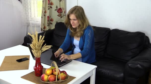 Έγκυος γυναίκα εργασίας υπολογιστή στο σπίτι, τρώνε κόκκινο ώριμο μήλο — Αρχείο Βίντεο