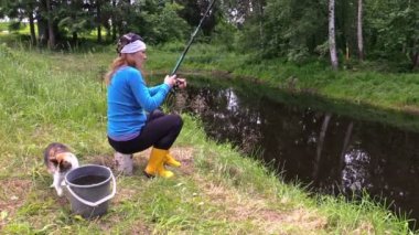 Hamile kadın güdük üzerinde oturmak ve sevimli tekir kedi ile balık yakalamak