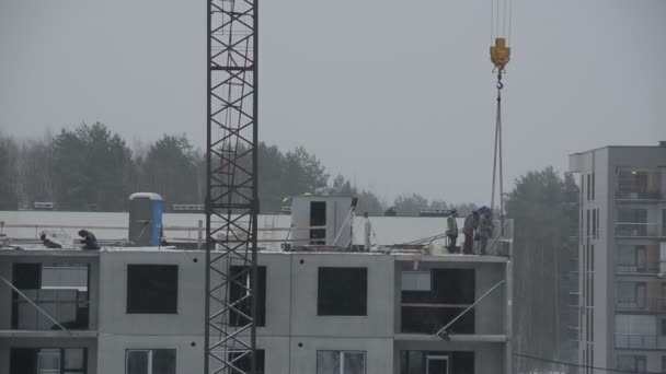 Trabajadores del sitio de construcción construyen casa de bloque. Nieve otoño en invierno — Vídeo de stock