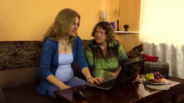 Genç kadın açıklamak merakla büyükanne bilgisayarınızı nasıl kullandığınızı. — Stok video