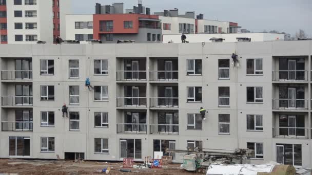 Risky construction site works. High wall insulation hang on rope — Stock Video