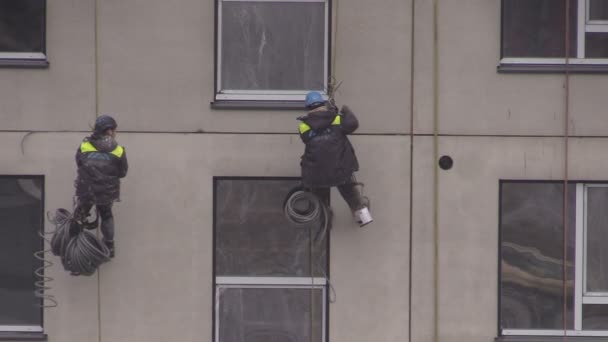 Builders climbers work hanging with rope on house wall — Stock Video