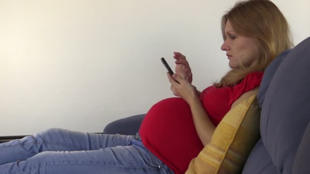 Cute pregnant woman browse photos and internet with smart phone — Stock Video