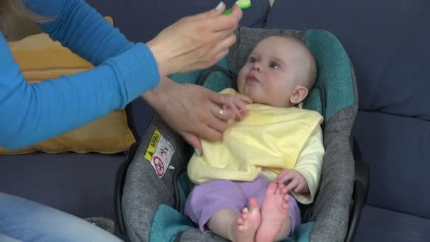 Bebê com babete amarelo comer pap vegetal sentado no assento do carro — Vídeo de Stock