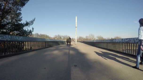 Parejas jóvenes caminan por el puente y hablan. 4K — Vídeo de stock