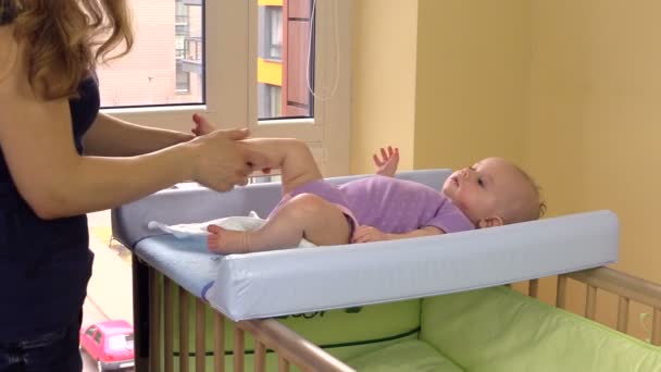 Mother massage and exercise her little baby daughter legs on bed — Stock Video