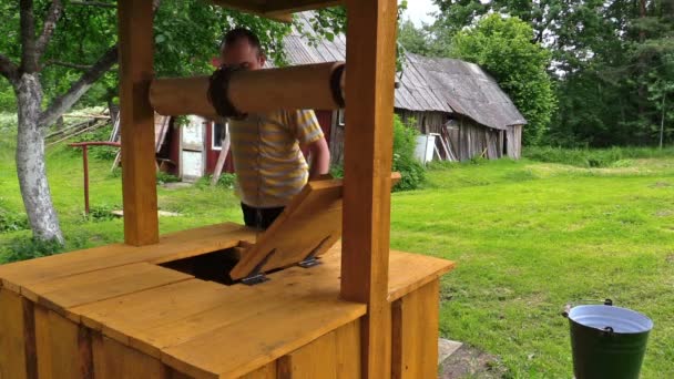 Muž žloutnout, malované dobře rukojeť a nakreslete plný kýbl vody — Stock video