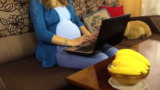 Trött gravid kvinna som arbetar med laptop. Bord med banan vas — Stockvideo