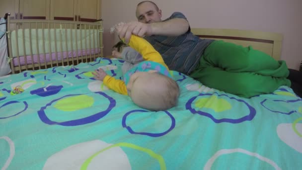 Vader man helpen zijn baby dochter omdraaien op bed thuis. 4k — Stockvideo