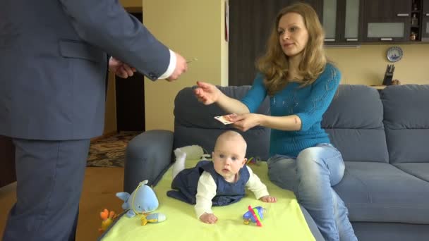 Женщина с ребенком на диване берет деньги у мужчины главы семьи. 4K — стоковое видео