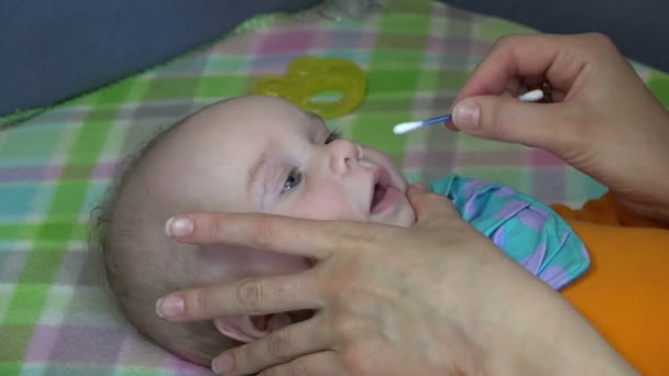 Baby face and woman hand with cotton stick clean nose. 4K — Stock Video