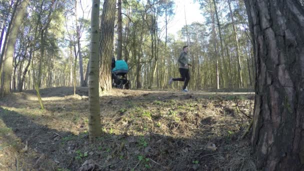 Jogger i matka push wózek dziecka w ścieżki parku wiosny. 4k — Wideo stockowe
