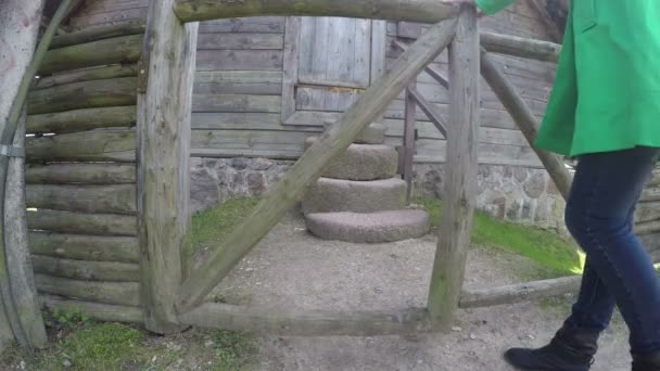 Fille en manteau vert ouvert porte en bois et monter sur escalier en pierre. 4K — Video
