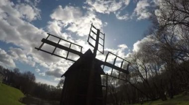 Ahşap retro değirmen siluet mavi bulutlu gökyüzü üzerinde. Timelapse. 4k