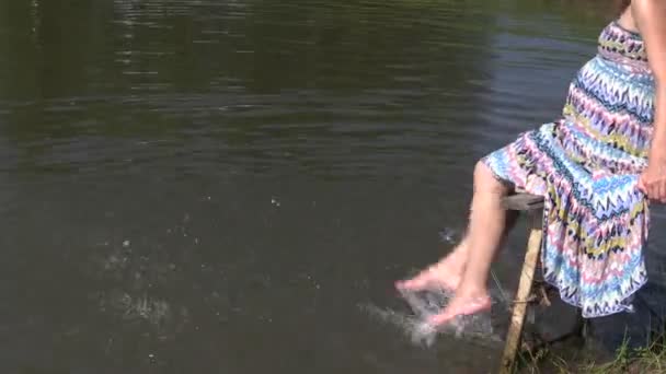 Pregnant girl splash feet in pond sit wooden bridge. Summer fun — Stock Video