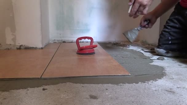 Hand glue ceramic tile slice on kitchen floor — Stock Video