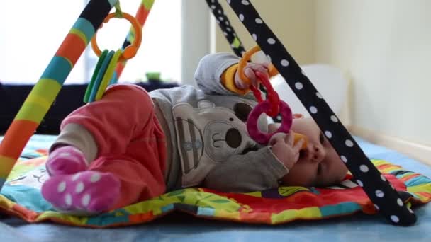 Jeu d'enfant avec jouet en caoutchouc se trouvent sur le tapis et rouler sur l'estomac — Video