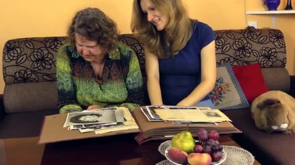 Granny with granddaughter looking long at photo from old album — Stock Video