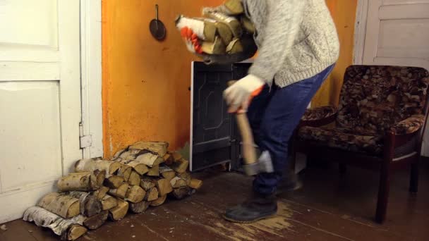 Man with woolly sweater bring wood, leave axe gloves near stove — Stock Video