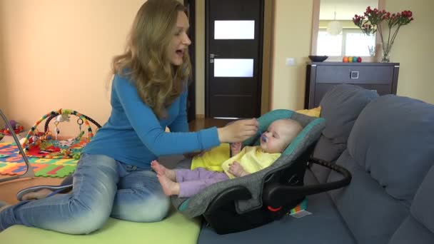 Jolie jeune femme nourrit son fils bébé avec une cuillère à la maison. 4K — Video