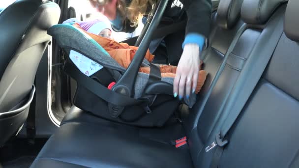 Frau befestigt Babystuhl mit Gurt auf der Rückbank des Autos. 4k — Stockvideo