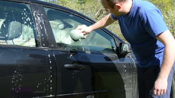 Hombre con esponja lavar coche en el jardín — Vídeos de Stock
