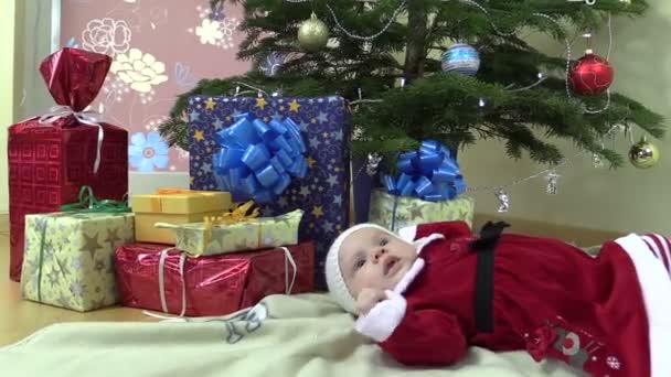 Niña bonita mentira cerca de árbol de Navidad y regalo regalo cajas — Vídeos de Stock