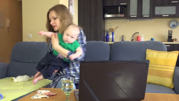 Hausfrau küsst Baby-Sohn und bezahlt Familienrechnungen mit Computer. 4k — Stockvideo