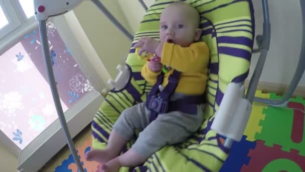 Lindo bebé con balanceo de juguete en columpio colorido en casa. 4K — Vídeo de stock
