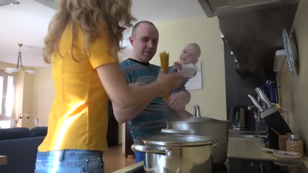 Uomo con bambino in mano e donna mettere gli spaghetti in pentola fumante. 4K — Video Stock