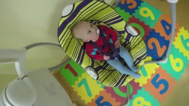 Baby pojke eller flicka gungning i färgglada Swing hemma. 4K — Stockvideo