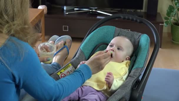 Ibu memberikan makanan untuk anaknya yang menggemaskan di rumah. 4K — Stok Video