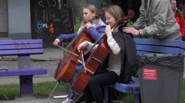genç kadın viyolonsel araç park bankında üzerinde oynamak. 4k