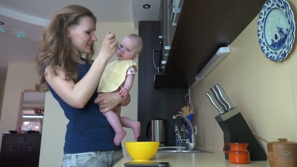Mother talk phone and feed baby on hands with spoon. 4K — Stock Video