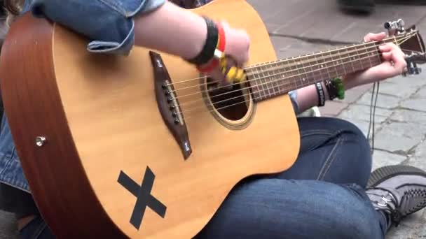 Las manos de la mujer juegan con el instrumento musical de guitarra acústica en el pavimento de la calle. 4K — Vídeo de stock