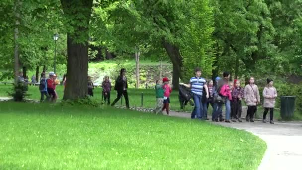 Děti se s průvodcem rozdělají v zeleném zahradním parku. 4k — Stock video