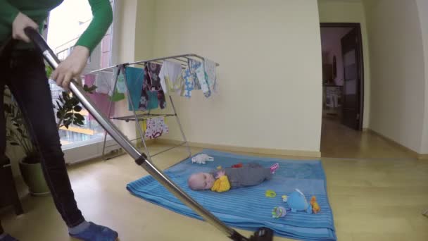 Frau kümmert sich um kleine Tochter und putzt Haus mit Staubsauger. 4k — Stockvideo
