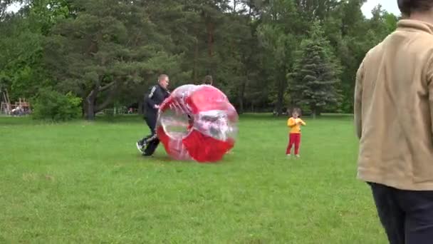 Padre empuje rápidamente a su hijo en la burbuja zorb en la hierba del prado. 4K — Vídeos de Stock