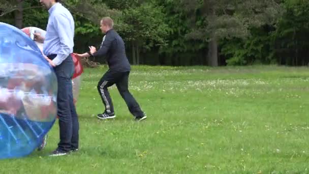 Padre empuje rápidamente a su hijo niño en zorb bola roja en el prado. 4K — Vídeo de stock