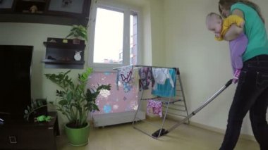 woman with baby on her hands clean floor with cleaner. 4K