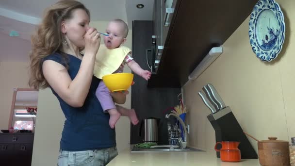 Moeder feed baby in keuken. Moederschap babyverzorging thuis. — Stockvideo