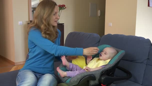 Mère nourrir belle fille bébé avec du porridge dans le siège d'auto . — Video