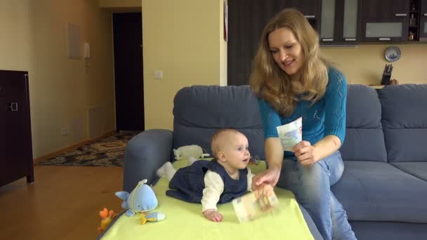 Mutter zeigt Baby-Tochter Euro-Geldscheine auf Sofa 4k — Stockvideo