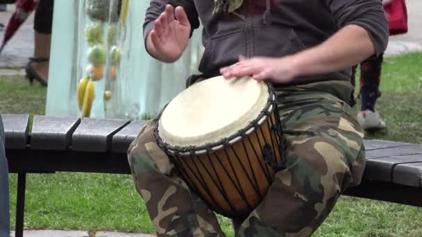 Musicien indéfini jouer le tambour africain assis sur le banc — Video