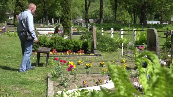 悲伤的男人收缩在母亲妻子墓在墓地附近。4 k — 图库视频影像