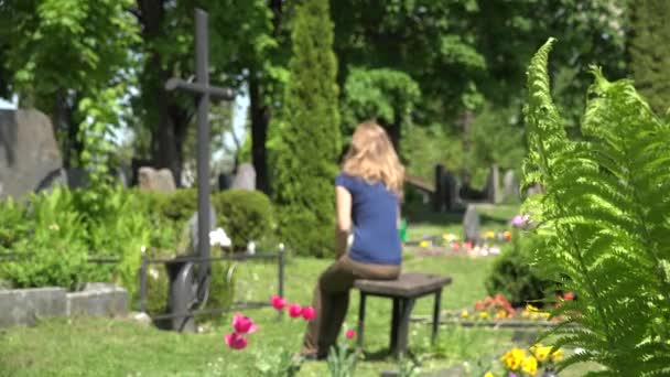 Menina estressada encolher perto de pai marido túmulo no cemitério. 4K — Vídeo de Stock